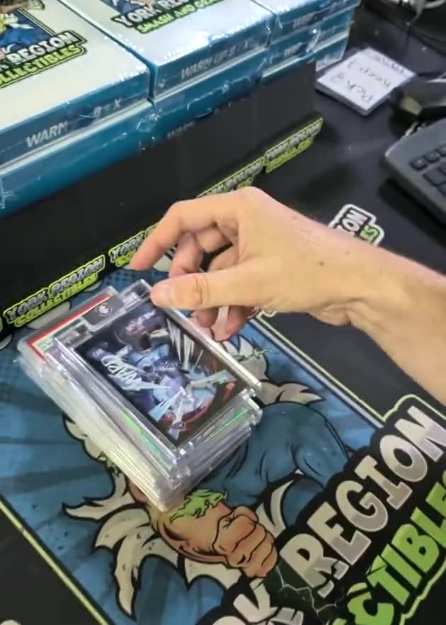 A graded slab held over the York Region Collectibles playmat